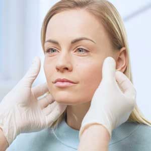 women at TMJ consult with dentist hands on jaw